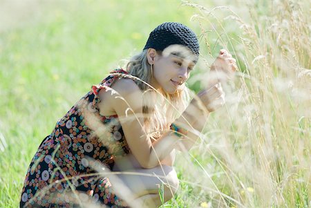 simsearch:633-01574151,k - Young woman crouching in field, touching tall grass Stock Photo - Premium Royalty-Free, Code: 633-01714141