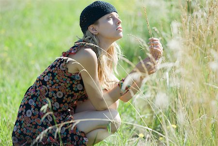simsearch:633-01574151,k - Young woman crouching in field, touching tall grass and looking up Stock Photo - Premium Royalty-Free, Code: 633-01714142