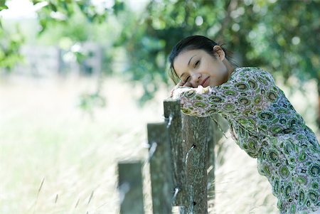 simsearch:633-01574151,k - Young woman leaning against rural fence, head resting on arms, smiling at camera Stock Photo - Premium Royalty-Free, Code: 633-01714181