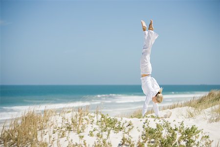 simsearch:633-01714467,k - Young woman doing handstand in dunes, ocean in background Stock Photo - Premium Royalty-Free, Code: 633-01714377