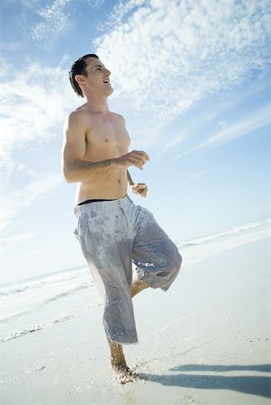 simsearch:633-01715682,k - Young man running through surf on beach, low angle view, full length Stock Photo - Premium Royalty-Free, Code: 633-01714457