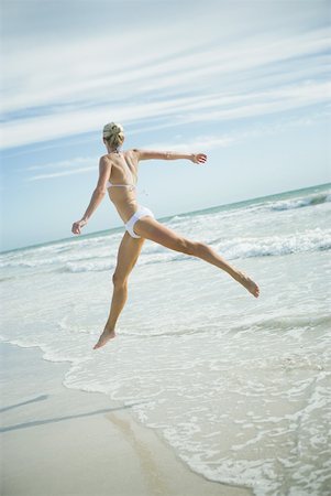 simsearch:633-01714467,k - Young woman in bikini, leaping in surf, in mid air Stock Photo - Premium Royalty-Free, Code: 633-01714470