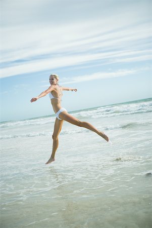 simsearch:633-01714467,k - Young woman in bikini, leaping in surf, in mid air Stock Photo - Premium Royalty-Free, Code: 633-01714473