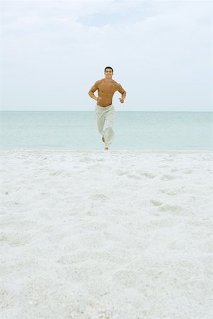 simsearch:633-01714467,k - Man running on beach, facing camera, ocean in background, full length Stock Photo - Premium Royalty-Free, Code: 633-01715183