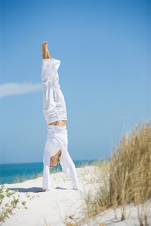 simsearch:633-01714467,k - Young woman doing handstand on dune, overlooking ocean Stock Photo - Premium Royalty-Free, Code: 633-01715670