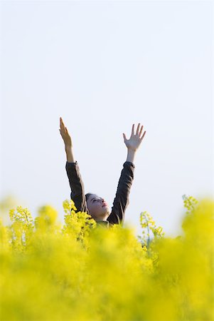 Girl standing in field with arms raised, looking up at sky Stock Photo - Premium Royalty-Free, Code: 633-01715820