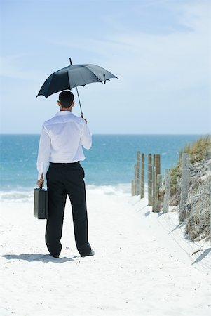 simsearch:632-03500607,k - Businessman standing under umbrella on sandy path leading to ocean, rear view Stock Photo - Premium Royalty-Free, Code: 633-01713837