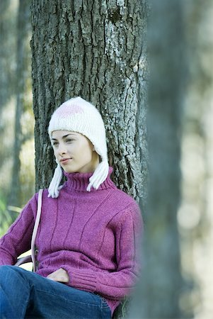simsearch:633-01574151,k - Young woman sitting on ground, leaning against tree, wearing knit hat and sweater Stock Photo - Premium Royalty-Free, Code: 633-01713948