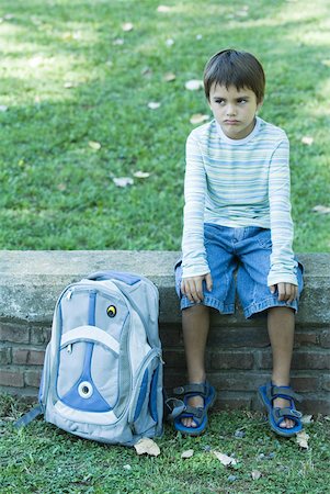 Boy sitting on low wall, backpack by side, looking away Stock Photo - Premium Royalty-Free, Code: 633-01713969