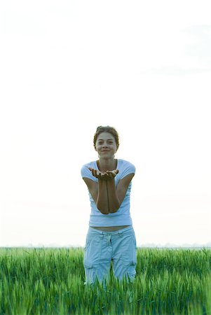 simsearch:400-05697219,k - Teenage girl standing in field, holding out cupped hands, smiling at camera Stock Photo - Premium Royalty-Free, Code: 633-01992407