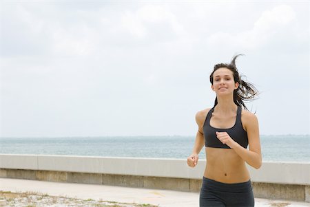 simsearch:633-01715682,k - Young woman running at the beach, hair tousled, smiling Stock Photo - Premium Royalty-Free, Code: 633-01992441
