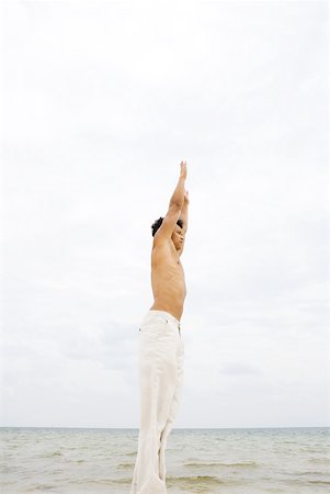 simsearch:632-01145004,k - Homme debout en face de l'océan, qui s'étend de bras supérieur, vue latérale Photographie de stock - Premium Libres de Droits, Code: 633-01992645