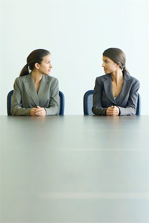 Teenage twin sisters dressed in suits, sitting at table, looking at each other Foto de stock - Sin royalties Premium, Código: 633-01992773