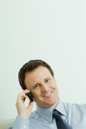 simsearch:695-03376228,k - Businessman using cell phone, head tilted, smiling at camera Stock Photo - Premium Royalty-Free, Code: 633-01992796