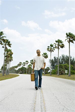 drifter - Man walking in center of road, carrying suitcase, looking down Stock Photo - Premium Royalty-Free, Code: 633-02044604