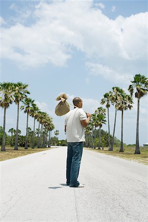 drifter - Man standing in middle of road, carrying burlap bundle on shoulder, rear view Stock Photo - Premium Royalty-Free, Code: 633-02044609