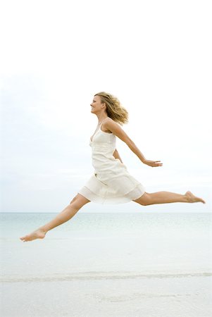 forward - Woman jumping in the air at the beach, side view Stock Photo - Premium Royalty-Free, Code: 633-02065824