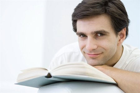 simsearch:632-03083700,k - Man resting chin on open book, smiling at camera Stock Photo - Premium Royalty-Free, Code: 633-02128679