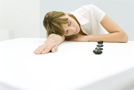 Woman resting head on table beside lined up stones Stock Photo - Premium Royalty-Free, Code: 633-02128833