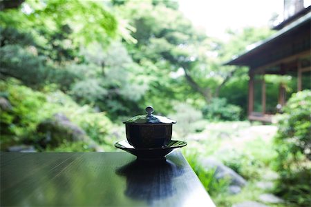 Covered tea cup and saucer on table, Japanese garden in background Stock Photo - Premium Royalty-Free, Code: 633-02417862