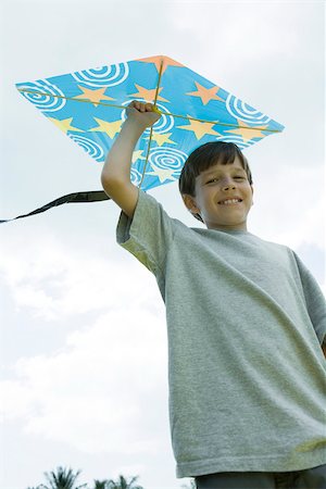 sky in kite alone pic - Boy holding kite above head, smiling at camera, low angle view Foto de stock - Sin royalties Premium, Código: 633-02417911
