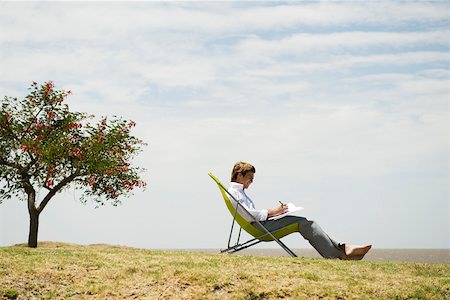 satisfacción - Man relaxing in lounge chair outdoors writing in notebook Foto de stock - Sin royalties Premium, Código: 633-03194784