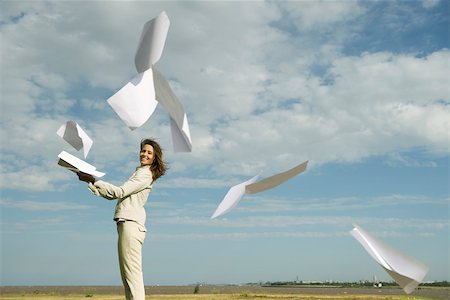 release - Woman outdoors tossing document into air watching pages caught by wind fly away Stock Photo - Premium Royalty-Free, Code: 633-03194814