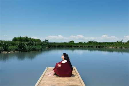 fresh air - Woman sitting on dock with blanket wrapped around her, eyes closed Stock Photo - Premium Royalty-Free, Code: 633-03444723