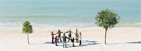 eight (quantity) - Group of people holding hands in circle between two trees on beach Stock Photo - Premium Royalty-Free, Code: 633-03444981