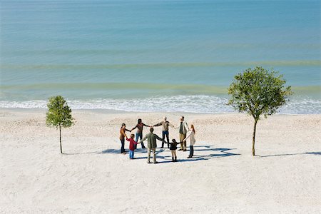 eight (quantity) - Group holding hands in circle on beach between two trees Stock Photo - Premium Royalty-Free, Code: 633-03444982