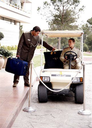 Bellboy driving hotel cart to deliver luggage to doorman Stock Photo - Premium Royalty-Free, Code: 644-01435908