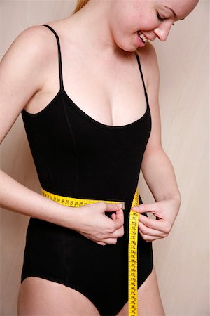 Woman measuring her waist Stock Photo - Premium Royalty-Free, Code: 644-01435992