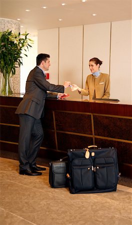 Man checking in  at the hotel reception desk Stock Photo - Premium Royalty-Free, Code: 644-01437379