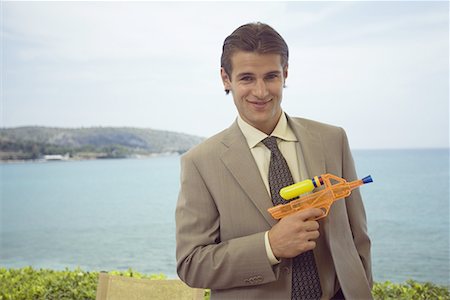 Homme d'affaires avec pistolet à eau en plastique Photographie de stock - Premium Libres de Droits, Code: 644-01631111