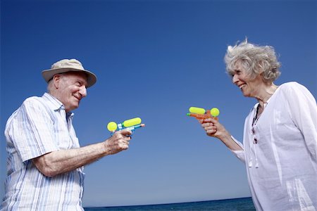 Senior couple on beach with water guns Stock Photo - Premium Royalty-Free, Code: 644-02060678