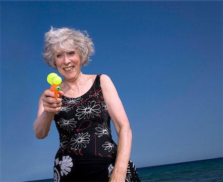 Female senior on beach with water gun Stock Photo - Premium Royalty-Free, Code: 644-02060681