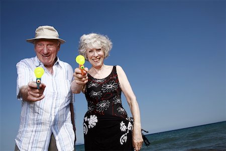 Senior couple on beach with water guns Stock Photo - Premium Royalty-Free, Code: 644-02060682