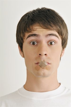Young male adult;Band-Aids over mouth Stock Photo - Premium Royalty-Free, Code: 644-02152805