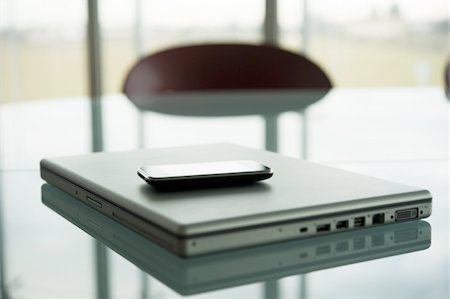 Laptop with cell phone on conference table Stock Photo - Premium Royalty-Free, Code: 644-02923182