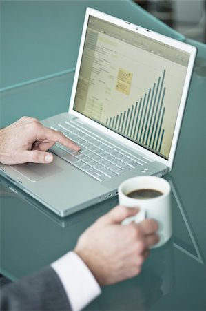 Businessman's hands with coffee cup at laptop with bar chart Stock Photo - Premium Royalty-Free, Code: 644-02923259
