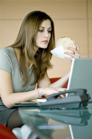 Businesswoman eating pita sandwich at laptop Stock Photo - Premium Royalty-Free, Code: 644-02923290