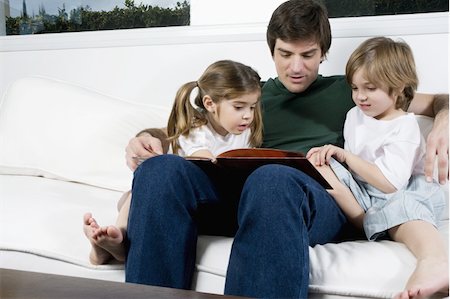 family, hotel - Young man on couch with children reading Stock Photo - Premium Royalty-Free, Code: 644-02923548