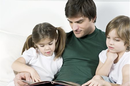 family, hotel - Young man on couch with children reading Stock Photo - Premium Royalty-Free, Code: 644-02923556