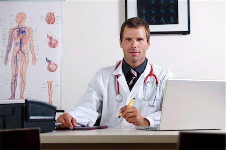 Doctor in his office with circulatory system chart and laptop Stock Photo - Premium Royalty-Free, Code: 644-03659668