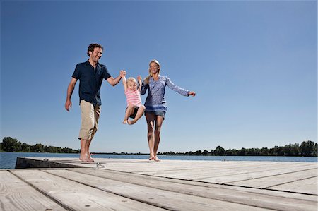 family playing on a jetty - Parents swinging daughter on dock Stock Photo - Premium Royalty-Free, Code: 649-04247699