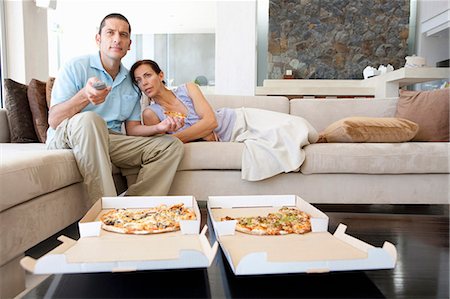 Couple manger la pizza dans le salon Photographie de stock - Premium Libres de Droits, Code: 649-04828709