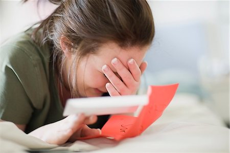 Crying teenage girl reading letter Stock Photo - Premium Royalty-Free, Code: 649-05648840
