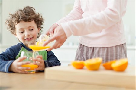 Mother pouring orange juice for son Stock Photo - Premium Royalty-Free, Code: 649-05657171