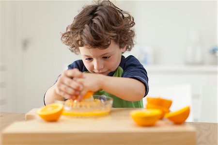 Boy squeezing oranges to make juice Foto de stock - Sin royalties Premium, Código: 649-05657172