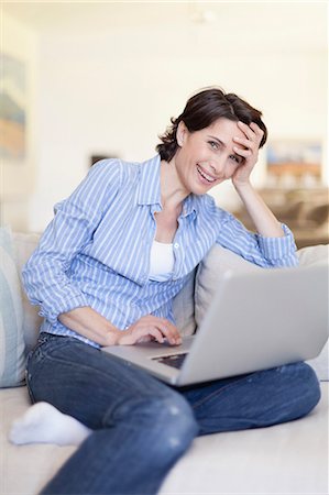 Smiling woman using laptop on couch Stock Photo - Premium Royalty-Free, Code: 649-05657216